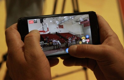 Live stream of a basketball game is displayed on a mobile phone.