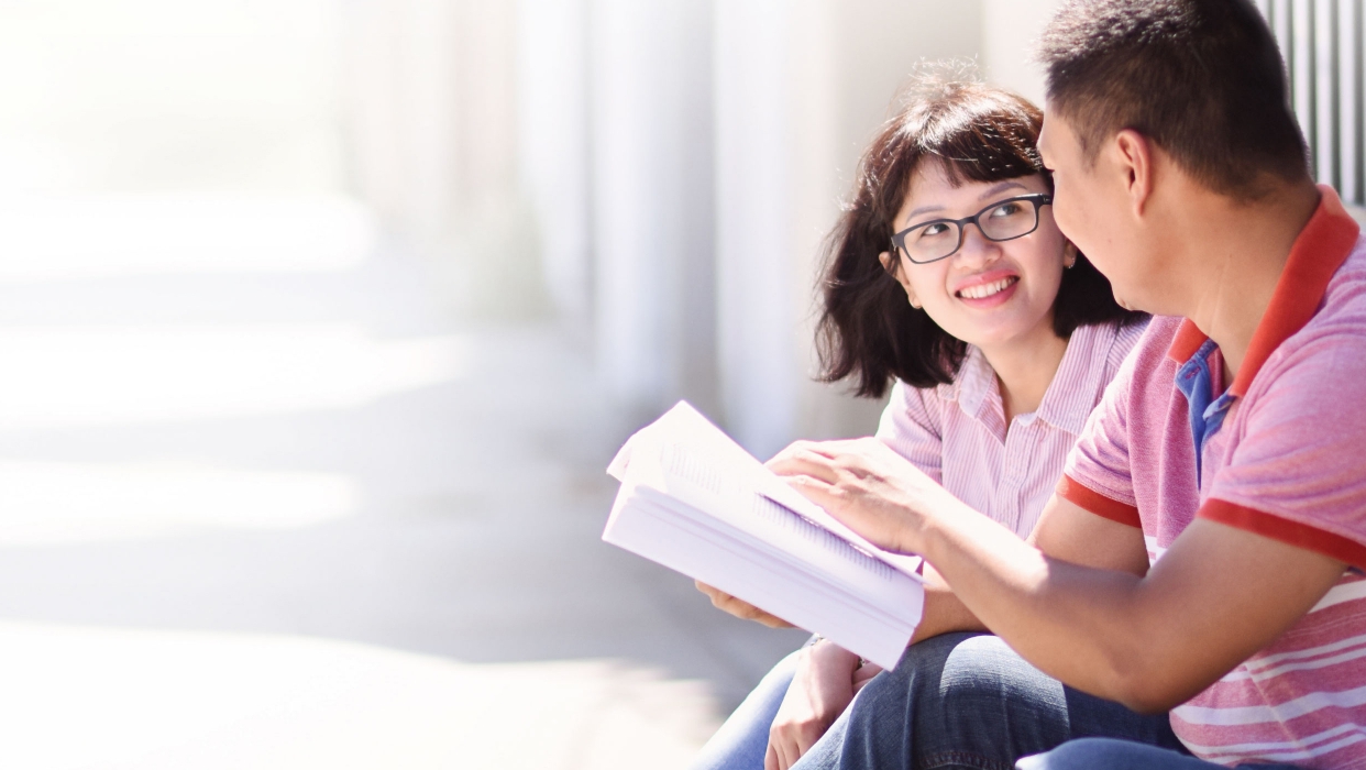 Two people hold a book