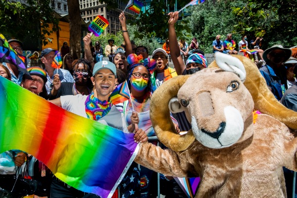 Rocky the Ram with students and rainbow flag