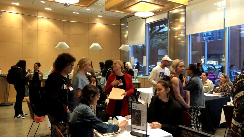 People talking at career fair tables, signing papers