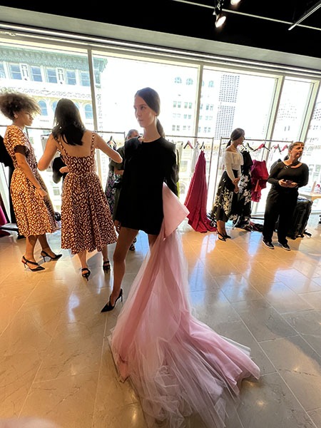 Model wearing a black dress with a pink train