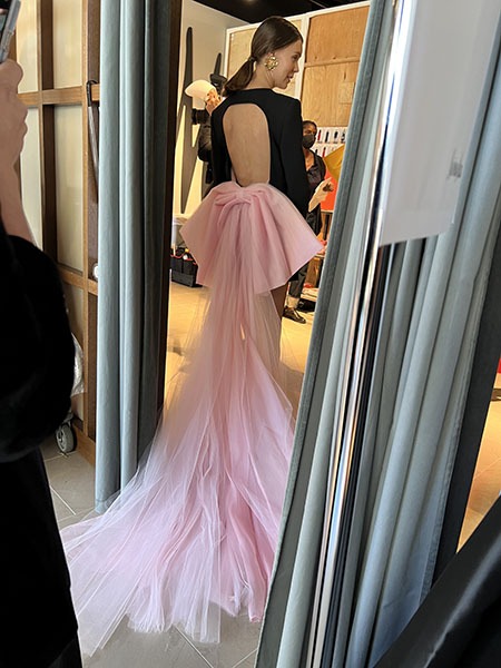 Model in black dress with a pink train